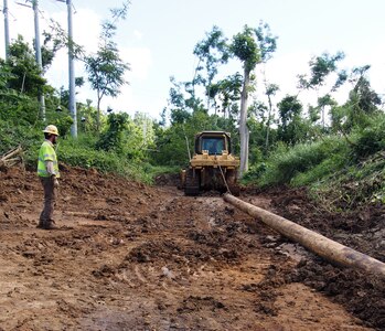 Emergency relief crews working with Army Corps of Engineers, Task Force Power Restoration, pull a wooden power pole up a newly created road to as part of the ongoing effort to restore power to the Trujillo Alto, Puerto Rico, Christmas Eve, 2017.  USACE is partnering with the Puerto Rico Electric Power Authority, the Department of Energy and FEMA and contracted partners, to restore safe and reliable power to the people of Puerto Rico. As assigned by FEMA, USACE leads the federal effort to repair the hurricane-damaged electrical power grid in support of the Government of Puerto Rico. Puerto Rico Electric Power Authority reports 59.4 percent or 875,500 of the 1.47M customers who are able to receive electric power have their service restored.