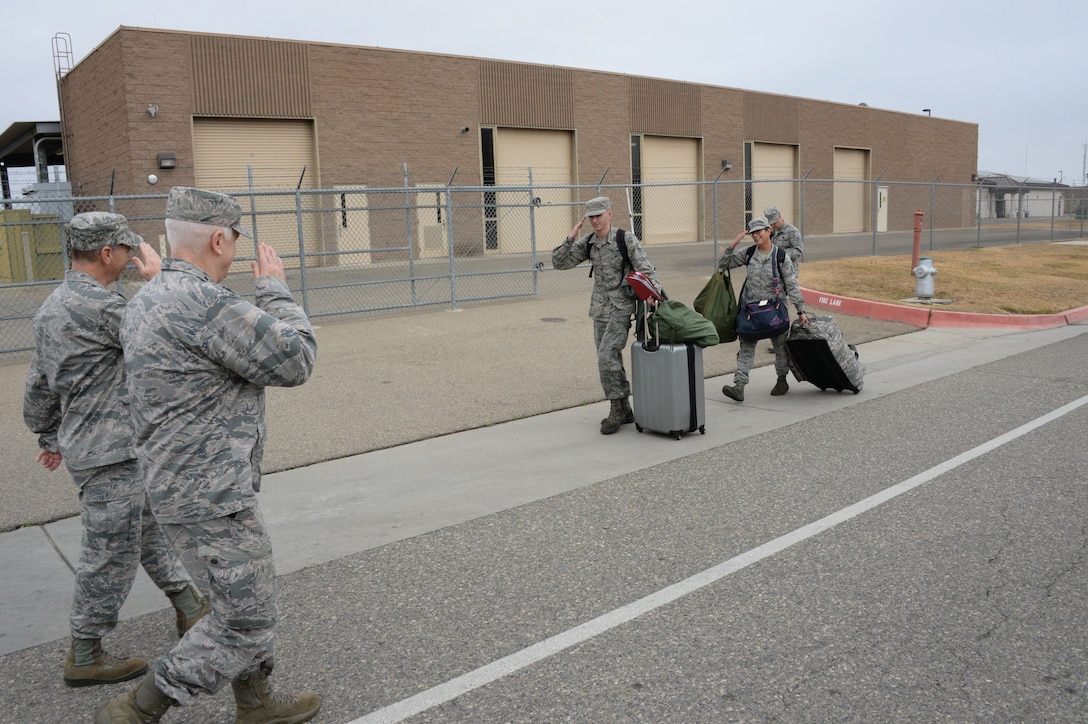 Lt. Gen. L. Scott Rice, the Director of the Air National Guard and Col. Reed Drake, the Commander of the 144th Fighter Wing exchange salutes with Airmen preparing to depart for a temporary duty assignment.