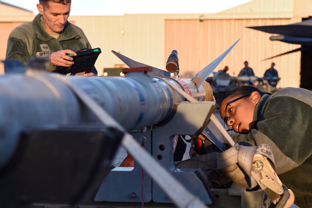 Two airmen inspect a missile.