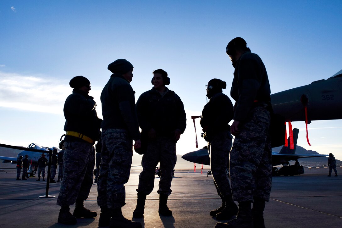 A group of airmen talk near an aircraft.