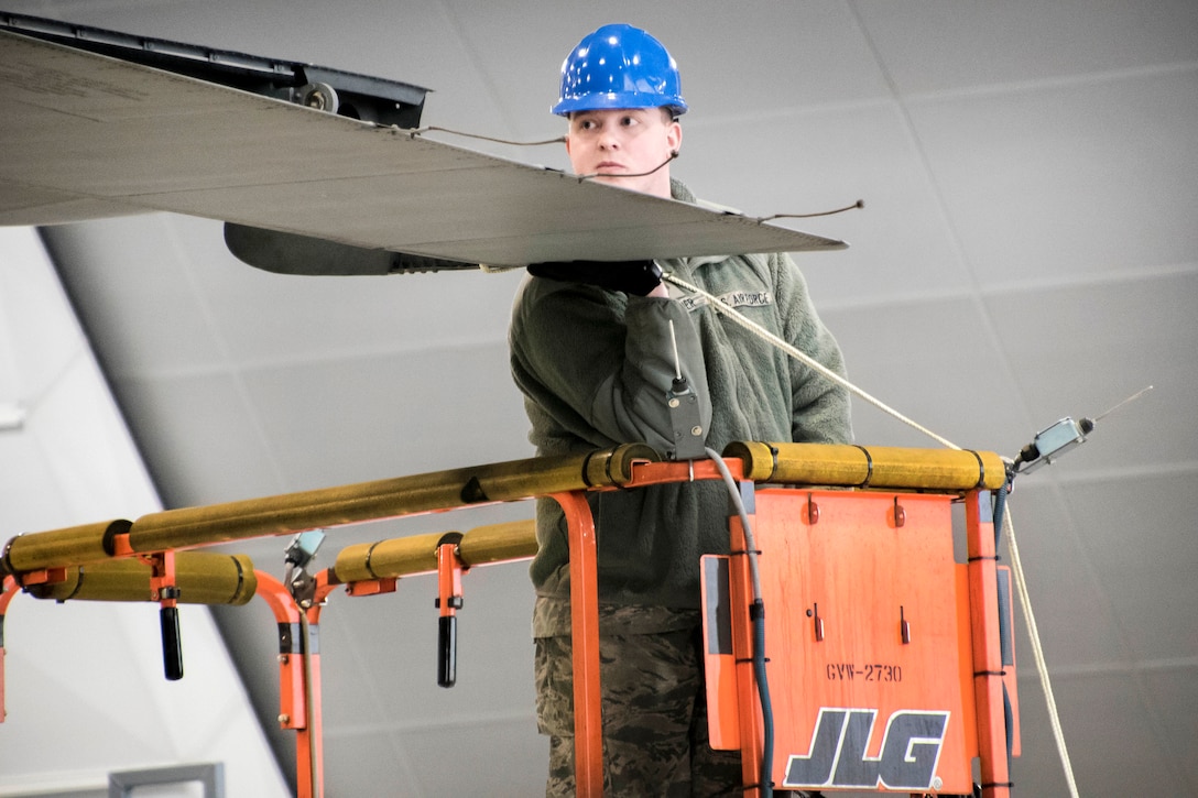 An airman holds a piece of an aircraft tail.