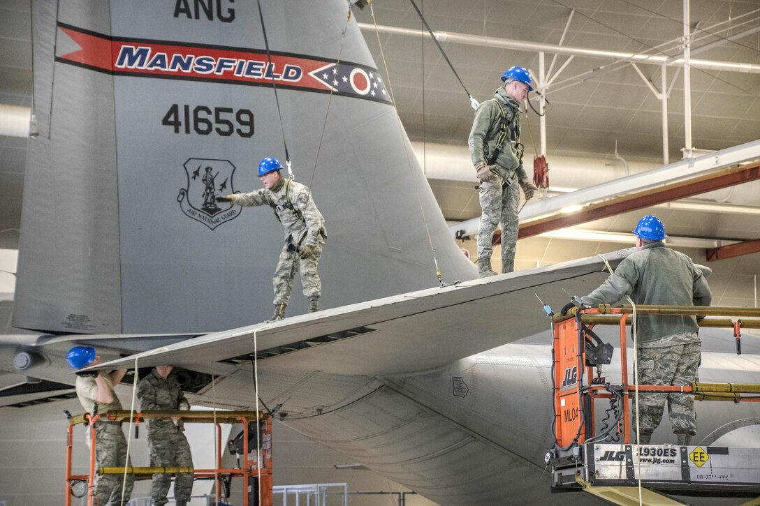 Airmen work on the tail on a large aircraft.