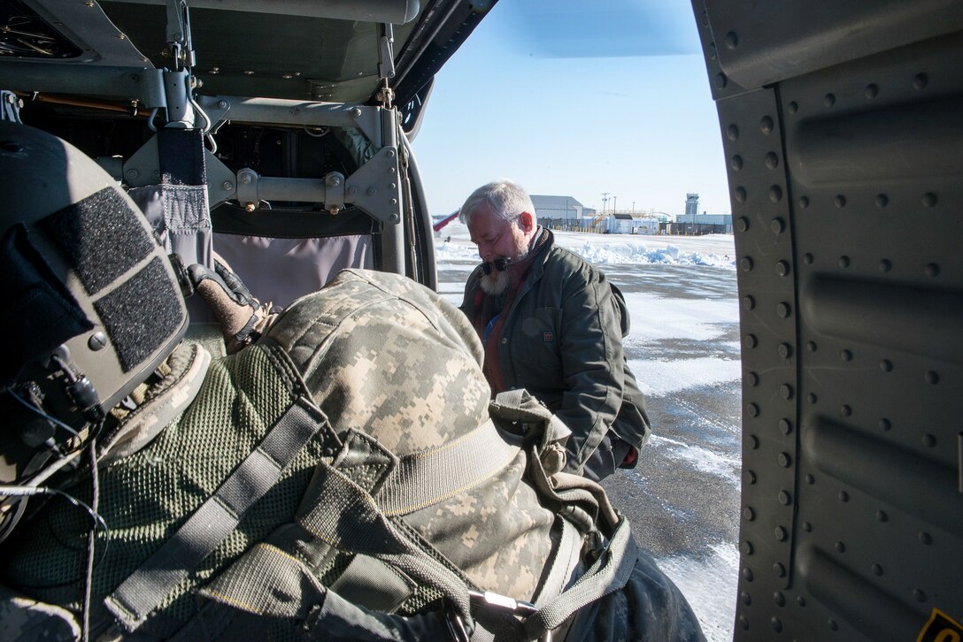 A National Guardsman loads equipment onto a helicopter.