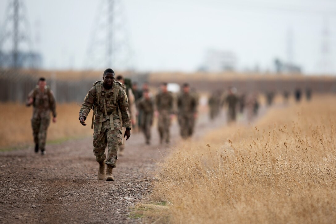 Soldiers march along a road.