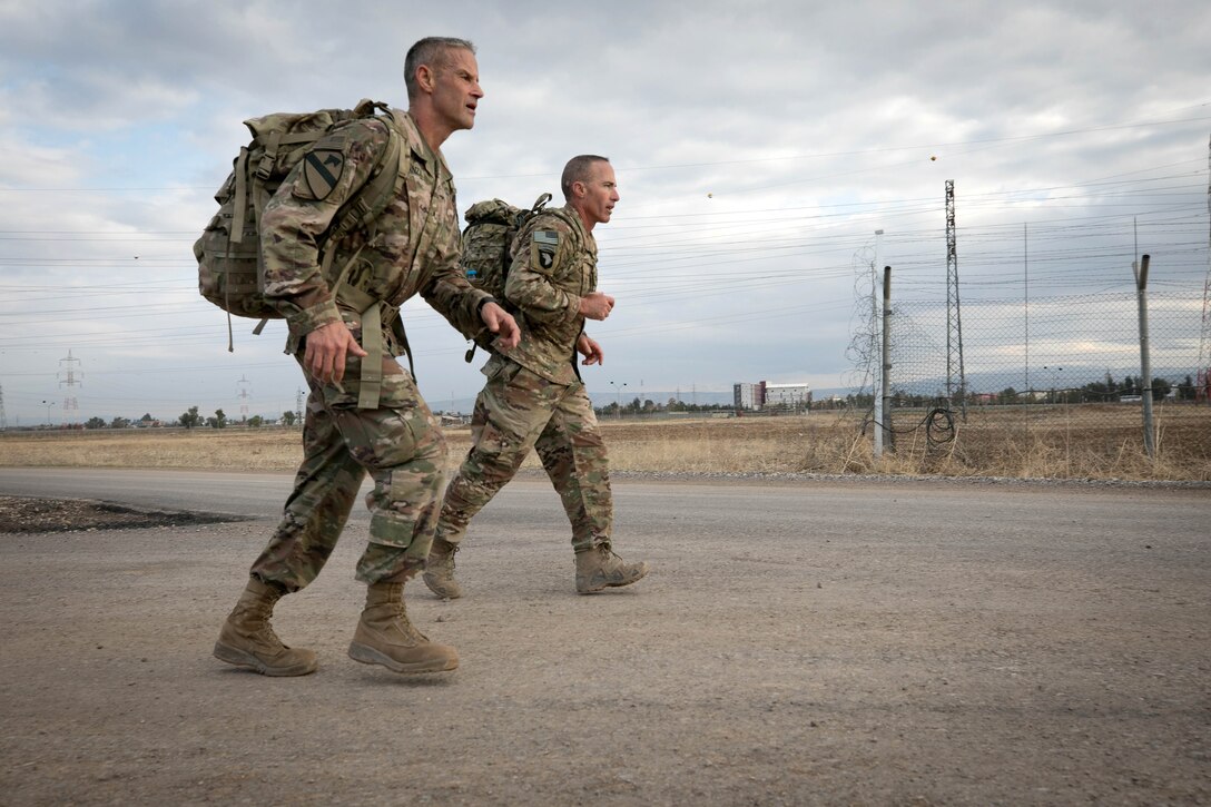 An Army and an Air Force officer march with packs together.