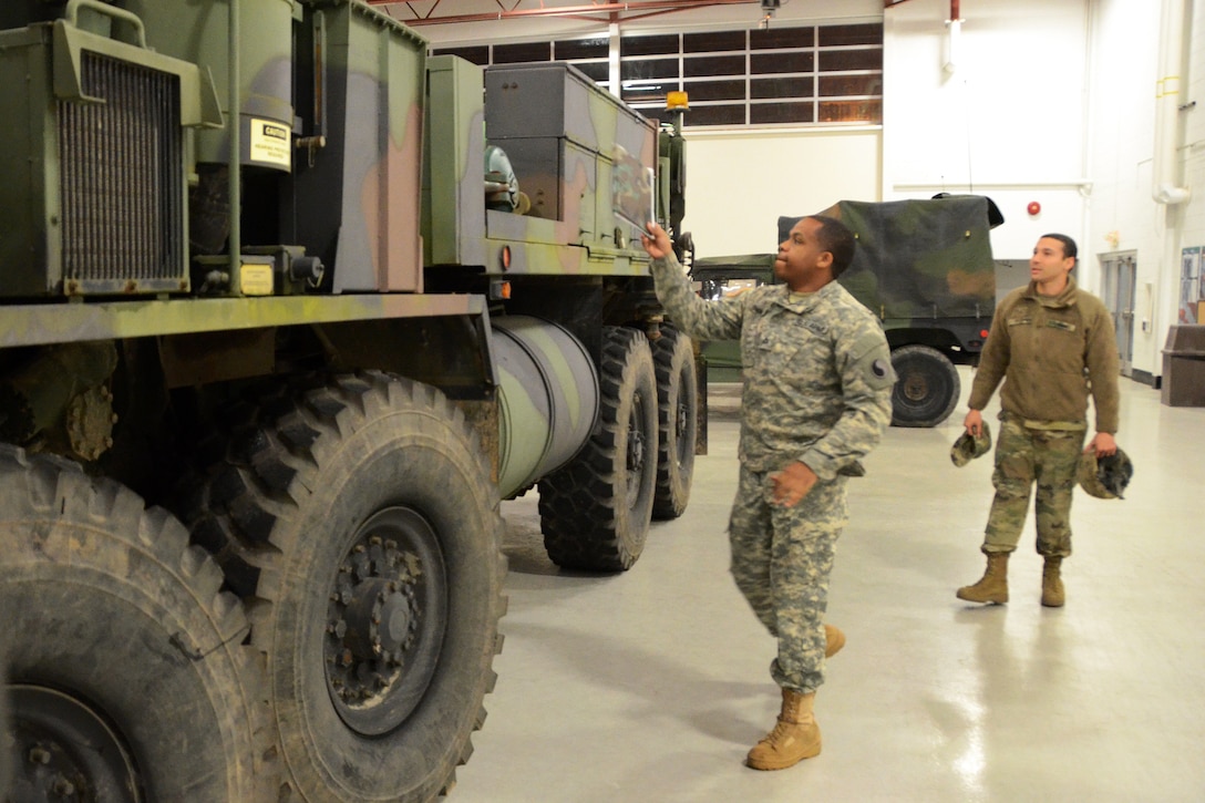 Guardsmen look at a military vehicle.