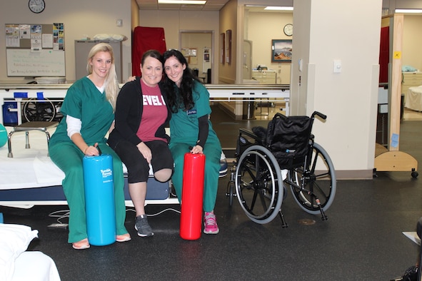 U.S. Air Force Medical Service Corps Officer, Maj. Stephanie Proellochs (center), works with two of Walter Reed National Military Medical Center’s physical therapists in Bethesda, MD, Nov. 8, 2017. Kyla Dunlavey (right) and Alyssa Olsen (left) work with the rest of Proellochs’ medical team throughout her amputation recovery.  Proellochs was diagnosed with a metastatic tumor in her left foot in January 2017, which resulted in having her foot amputated. (U.S. Air Force photo by Karina Luis)