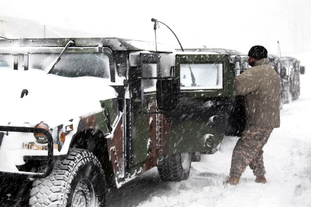 A guardsman opens the door to a Humvee during a snowstorm.