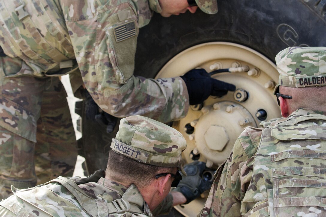 Soldiers change a tire on a truck.