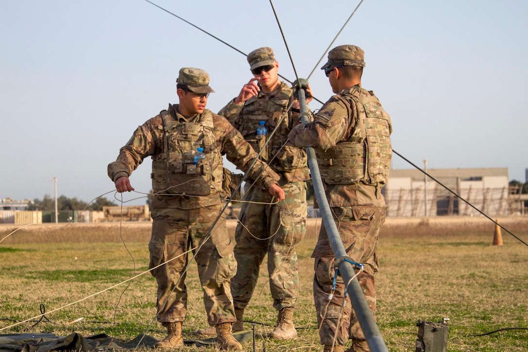 Soldiers set up an OE-254 antenna for radio communications system.