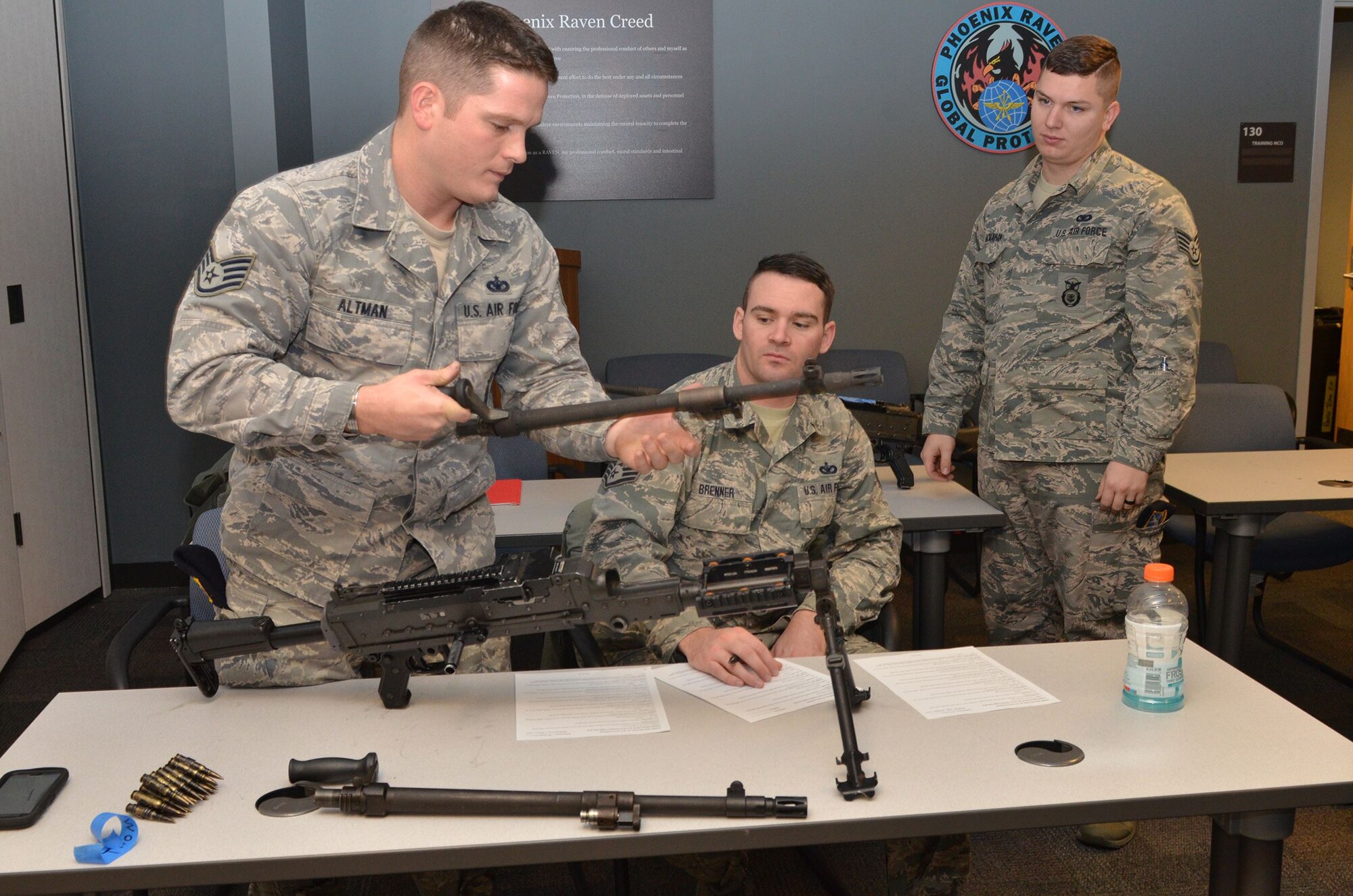 Staff Sgt. Jalen McMahan, right, looks on as Staff Sgt. Drew Brenner, middle, grades Staff Sgt. Kyle Altman disassembling his M-240B heavy machine gun during the 445th Security Forces Squadron heavy weapons familiarization training Dec. 17, 2017.