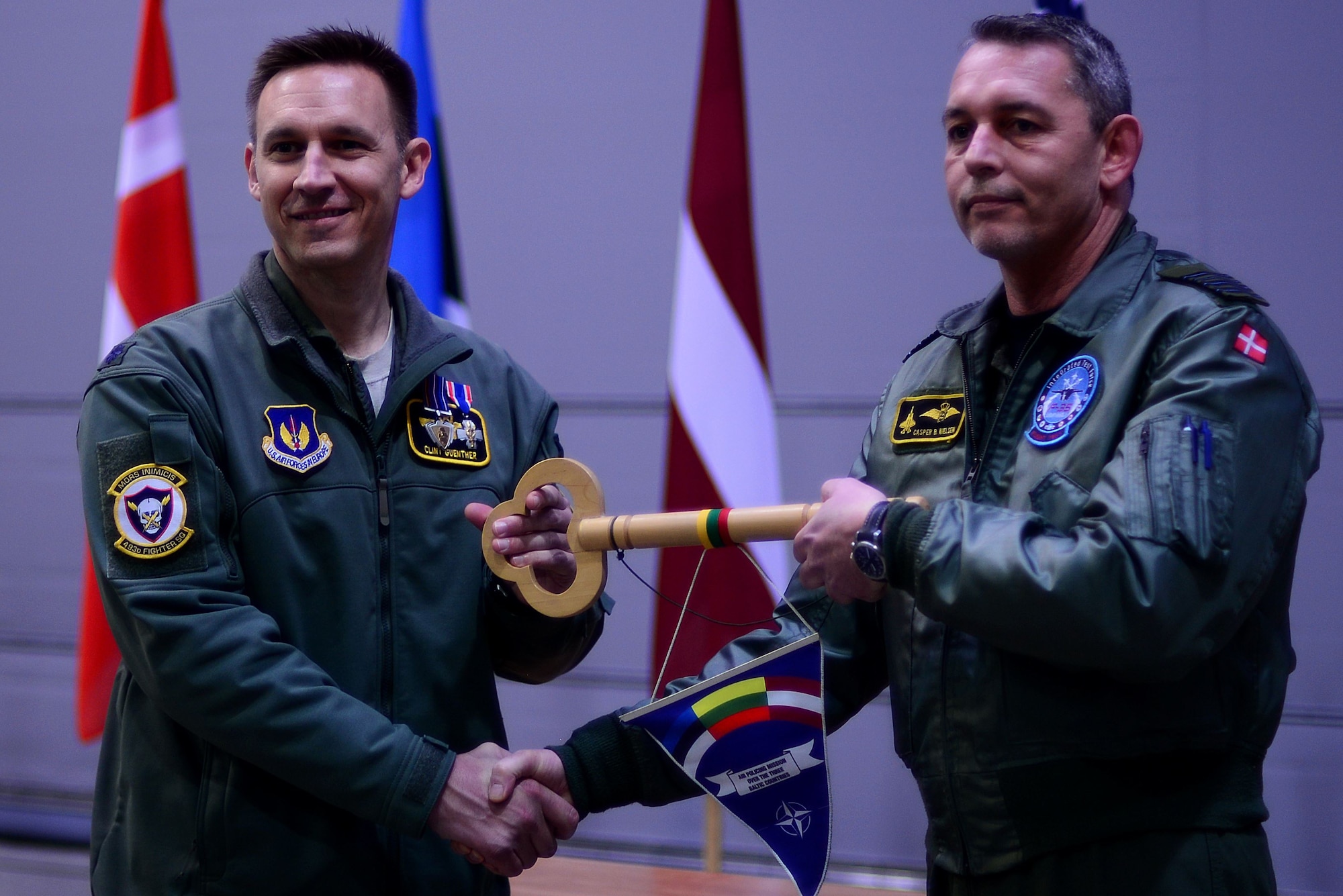 U.S. Air Force Lt. Col. Clint Guenther, 493rd Expeditionary Fighter Squadron detachment commander, presents the key to the Baltic Air Policing mission to Royal Dannish air force commander Col. Uffe Holstener during the official Baltic Air Policing hand-over, take-over ceremony at Šiauliai Air Base, Lithuania, Jan. 8, 2018. This is Denmark's sixth Baltic Air Policing rotation since operations began in 2004. (U.S. Air Force photo/ Tech. Sgt. Matthew Plew)