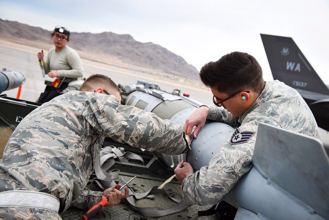 Airmen work together to transport a Mark 84 bomb to an F-35 Lightning II fighter aircraft.