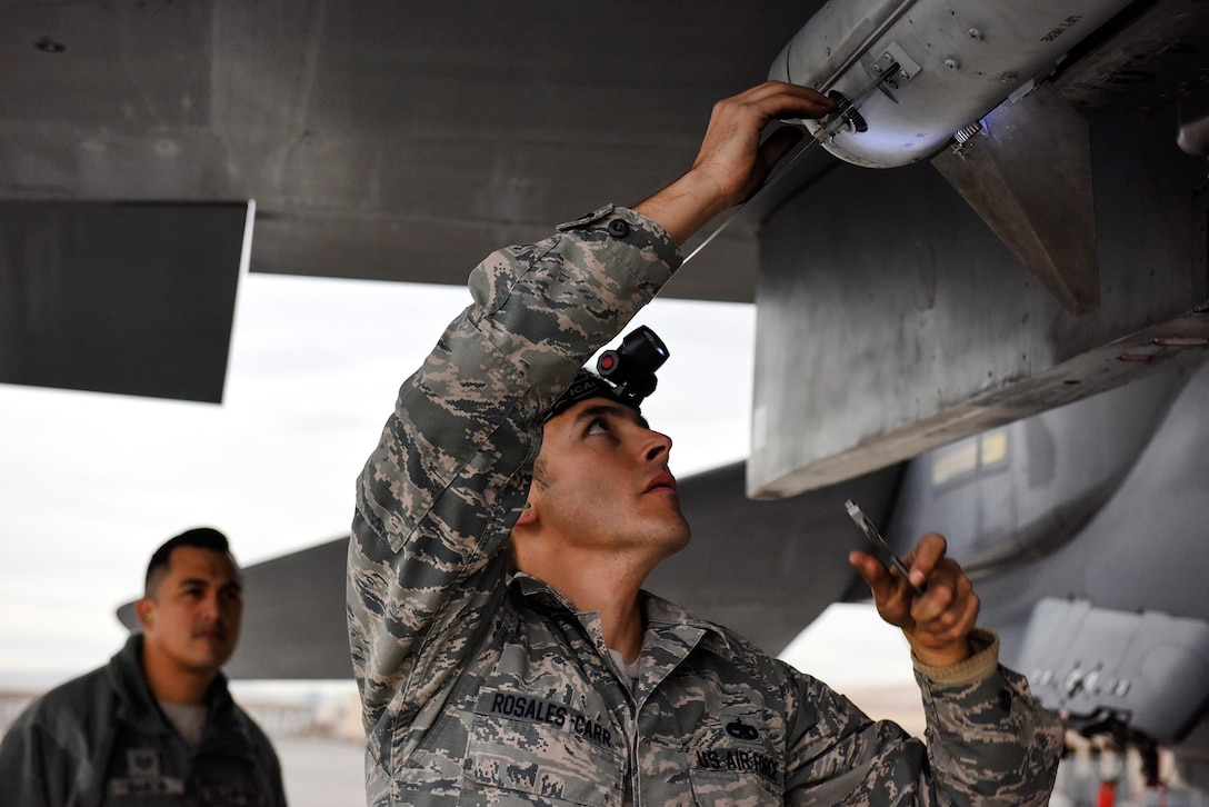 Staff Sgt. Brett Rosales-Carr adjusts pieces of an AIM-120 missile on an F-15 Eagle fighter aircraft.