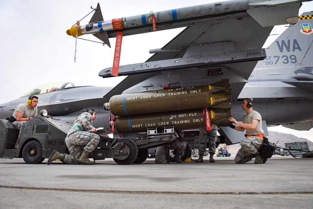 Airmen load munitions onto an F-16 Fighting Falcon fighter aircraft.
