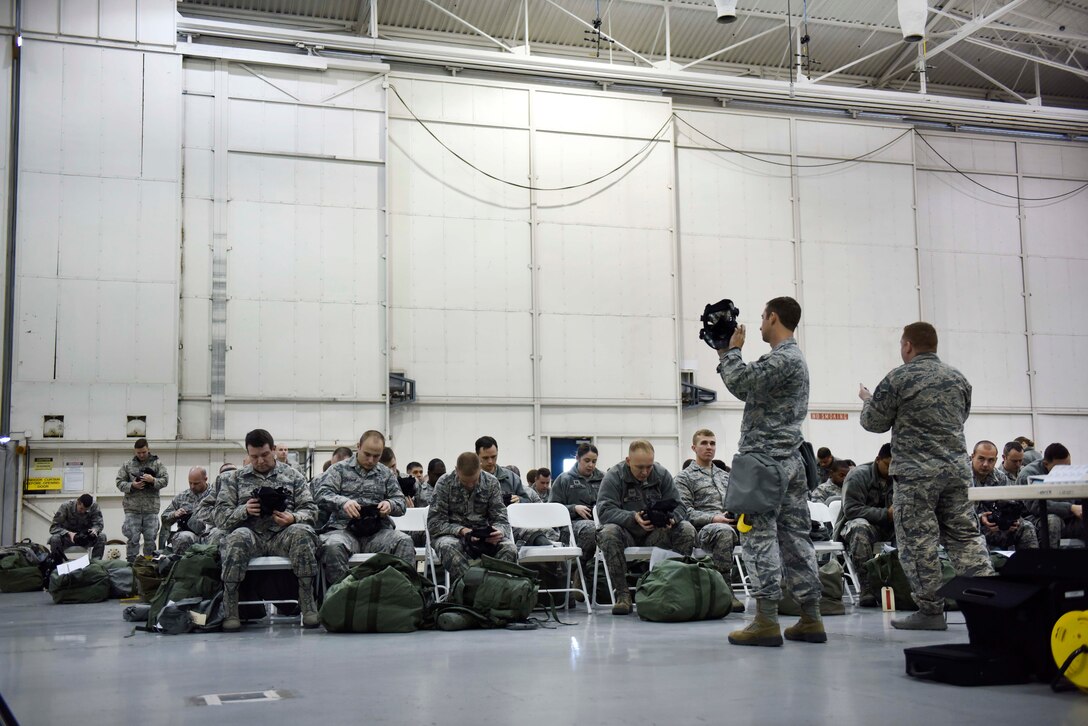 Airman instructs airmen on the proper procedures to inspect a gas mask.