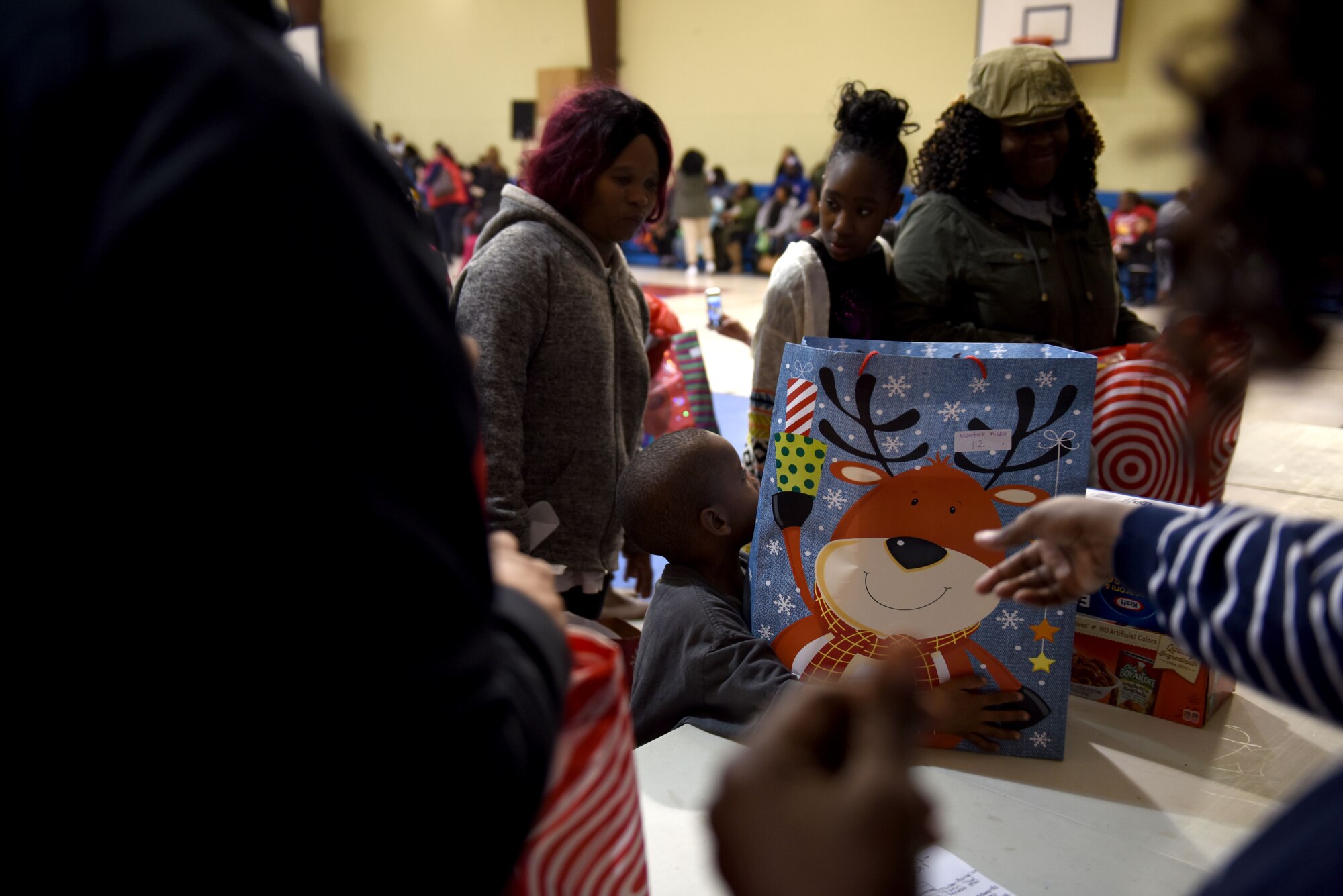 A young boy reaches for a present during Operation Santa held at the Aristotle Preparatory Academy, Dec. 16, 2017. Operation Santa is a local and annual event run by the Chapter 7 organization of the North Carolina Air National Guard. This year, the NCANG provided presents, lunch, music, face-painting, blankets, stuffed animals. They partnered with the local Target for food donations and a craft table, and inflatable castles through Garris and Wilson Entertainment. (U.S. Air National Guard photo by Staff. Sgt. Laura J. Montgomery)