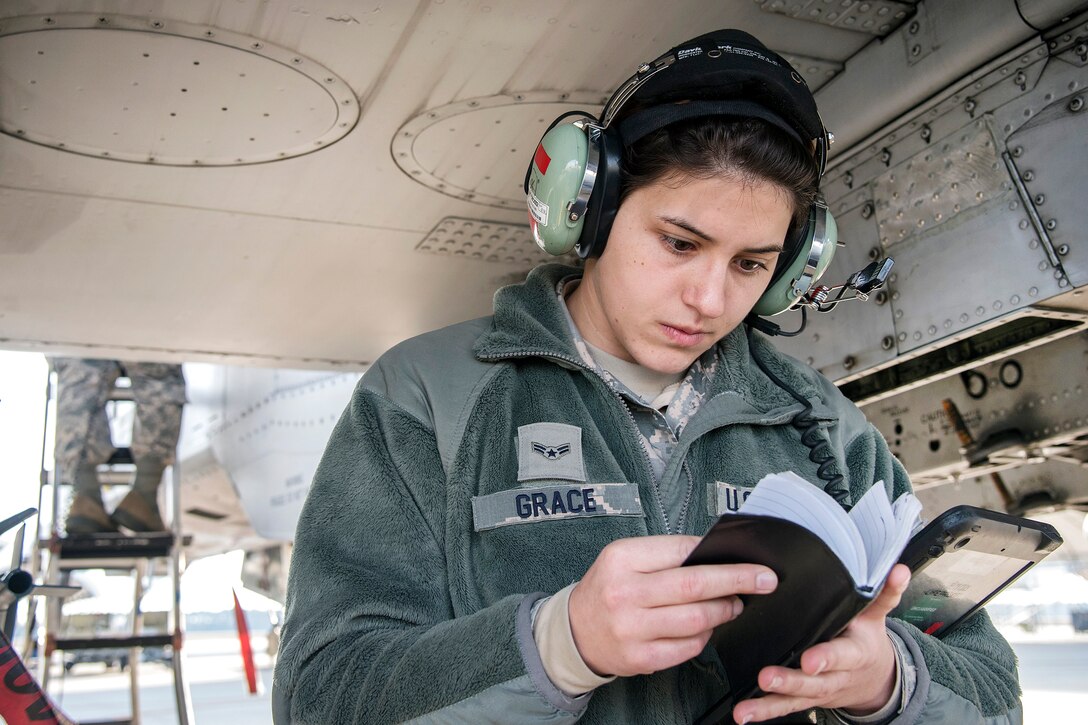 An airman reviews her notes while performing final checks on an A-10 Thunderbolt II aircraft.