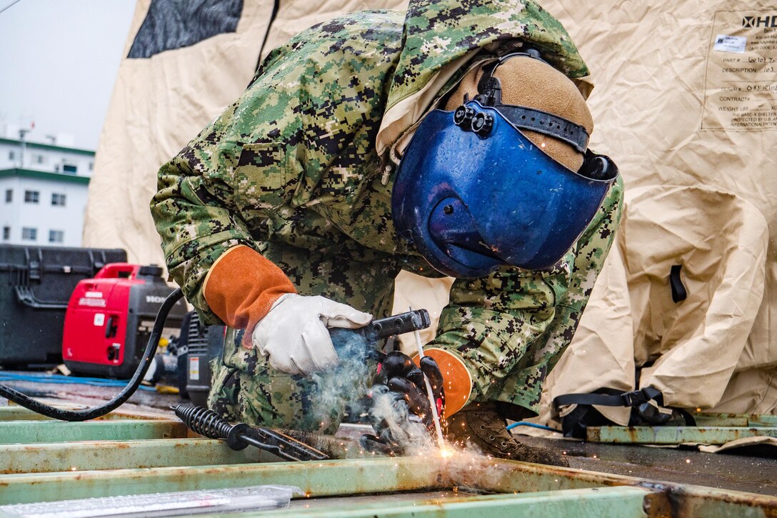 Navy Chief Jesse Hamblin repairs a ladder for an underwater pile removal operation
