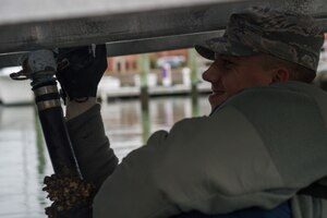U.S. Air Force Airman 1st Class Tyler Talbot, 633rd Civil Engineer Squadron water and fuel systems maintenance journeyman, hangs an emptied water pipe under the Langley Marina docs at  Joint Base Langley-Eustis, Va., Dec. 7, 2017.