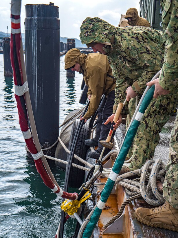 Navy Seabees provide surface support to divers during an underwater pile removal operation.