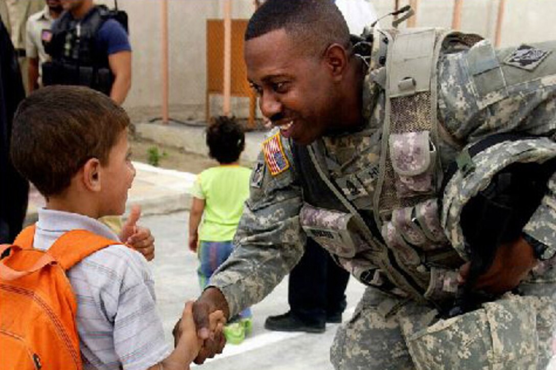 Army Sgt. Maj. Benny Hubbard shakes hands with an Iraqi child