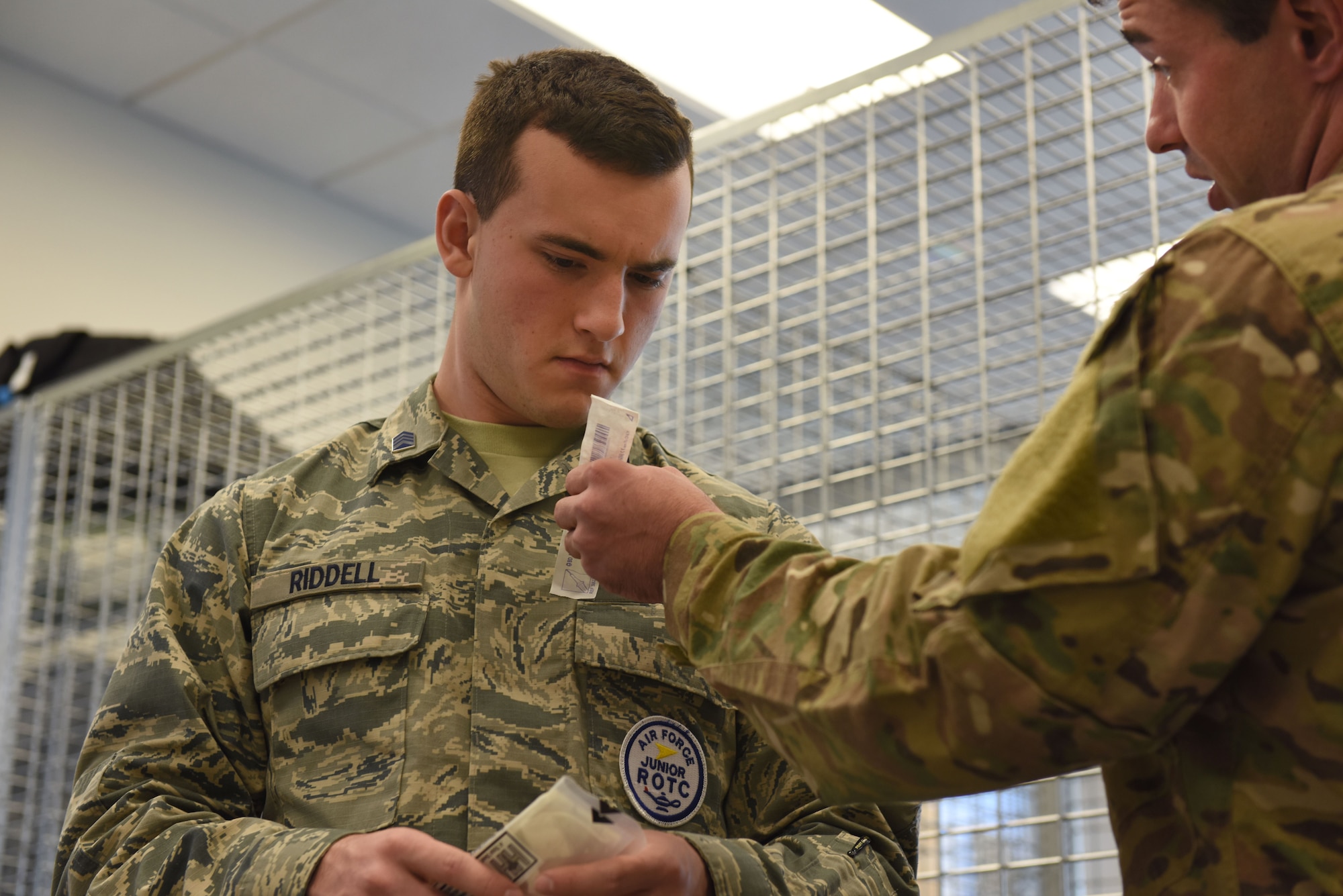 U.S. Air Force 2nd Lt. Nathan Closen, tactical air control party specialist assigned to the 118th Air Support Operations Squadron (ASOS), demonstrates to Chase Riddell, student from East Mecklenburg High School, field medical tactics during a visit Dec. 04, 2017. Riddell, with the junior reserves officer training corps (J.R.O.T.C.), reached out to the North Carolina Air National Guard to shadow a guardsmen as his senior project. Closen gave Riddell a tour of their facility, and equipment including a unique simulation room. (U.S. Air National Guard photo by Staff. Sgt. Laura J. Montgomery)