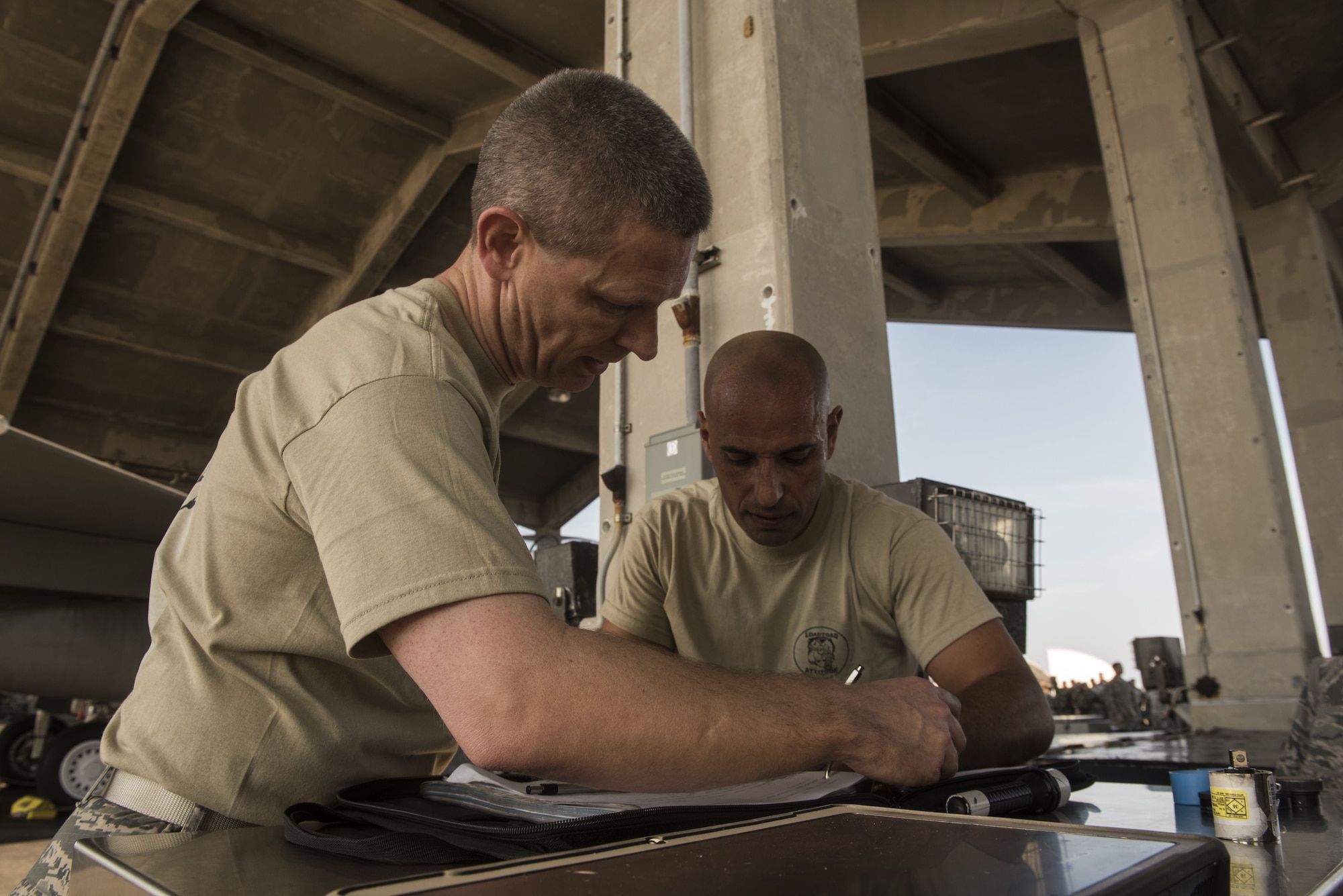 U.S. Air Force Col. Britt Hurst, left, 18th Operations Group commander, and Col. Tony Lombardo, 18th Maintenance Group commander, check forms during the Chiefs versus Eagles Weapons Loading competition Jan. 3, 2018, on Kadena Air Base, Japan. Each team had to load one AIM-9X heat seeking missile to the aircraft as quickly as possible. (U.S. Air Force photo by Staff Sgt. Micaiah Anthony)