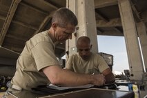 U.S. Air Force Col. Britt Hurst, left, 18th Operations Group commander, and Col. Tony Lombardo, 18th Maintenance Group commander, check forms during the Chiefs versus Eagles Weapons Loading competition Jan. 3, 2018, on Kadena Air Base, Japan. Each team had to load one AIM-9X heat seeking missile to the aircraft as quickly as possible. (U.S. Air Force photo by Staff Sgt. Micaiah Anthony)