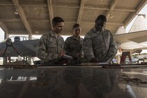 U.S. Air Force Staff Sgt. Michael McCoy, left, 18th Maintenance Group weapons load crew chief, Airman 1st Class Victoria Barsness, center, 18th MXG weapons load crew member, and Tech. Sgt. John Cummings, 18th MXG loading standardization crew member, calculate scores during the Chiefs versus Eagles Weapons Load Competition Jan. 3, 2018, on Kadena Air Base, Japan. The competition pitted a team of chief master sergeants against a team of colonels on who could prepare the aircraft for combat the fastest with the fewest procedural errors. (U.S. Air Force photo by Staff Sgt. Micaiah Anthony)