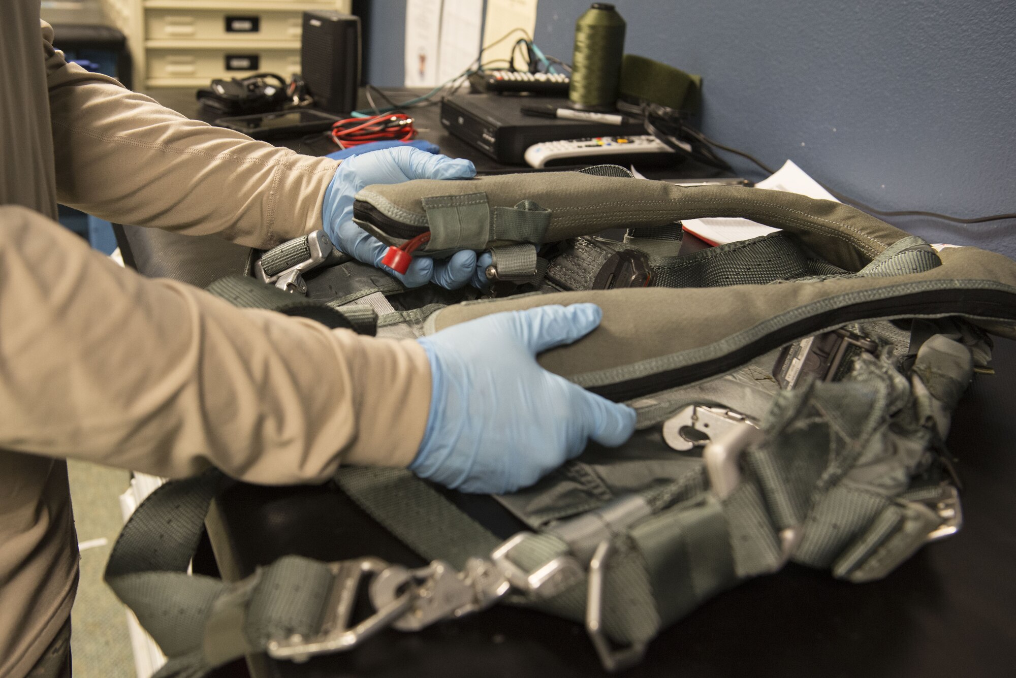 Airman 1st Class Conner Scott, an aircrew flight equipment journeyman with the 3rd Operations Support Squadron, inspects an inflatable life jacket at Joint Base Elmendorf-Richardson, Alaska, Jan. 5, 2018. Inflatable life jackets activate when water is detected or can be deployed manually by the wearer.