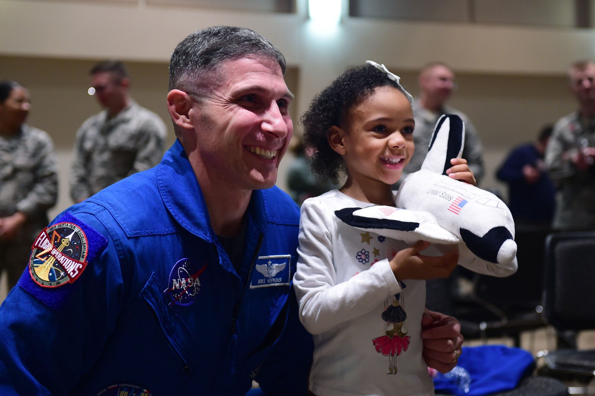 Col. Michael S. Hopkins, astronaut, Air Force National Aeronautics Space Agency, takes a photo with a child the Leadership Development Center, Buckley Air Force Base, Colo., Jan. 8, 2018. The child was upset she was unable to ask Hopkins a question during his presentation so he took time after to take a photo and speak with the little girl about being an astronaut. (U.S. Air Force photo by Senior Airman Luke W. Nowakowski)