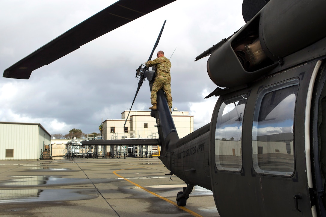 Chief Warrant Officer 5 Robert Metoyer inspects the tail rotor blades on a UH-60 Black Hawk helicopter.