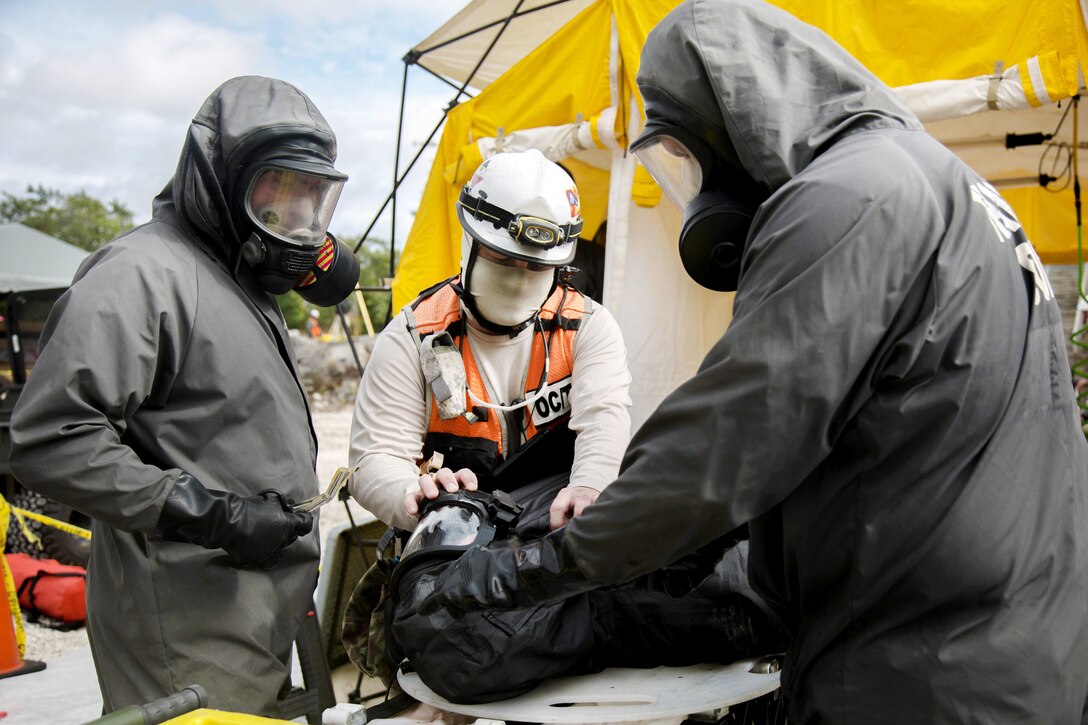 Army Reserve soldiers check the protective gear before providing medical aid to mock casualty.