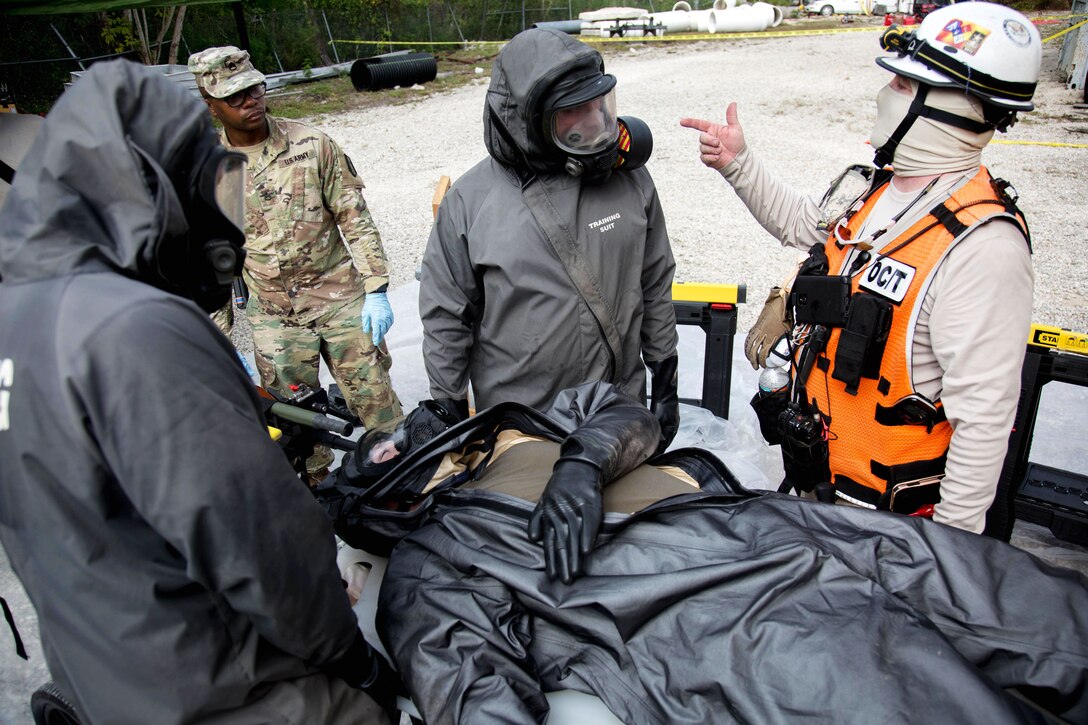 Army Reserve soldiers talk with an observer controller on the next procedure after providing medical aid to mock casualty.