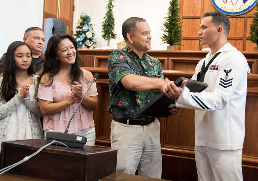 Navy Petty Officer 1st Class Anthony Mugavero, a master at arms assigned to U.S. Naval Base Guam Harbor Patrol, receives a legislative resolution from Guam Sen. Dennis Rodriguez Jr. at the Guam Congress Building in Hagatna, Guam, Dec. 29, 2017. While visiting a mall in nearby Dededo, Mugavero pursued a thief to retrieve a stolen purse. Navy photo by JoAnna Delfin