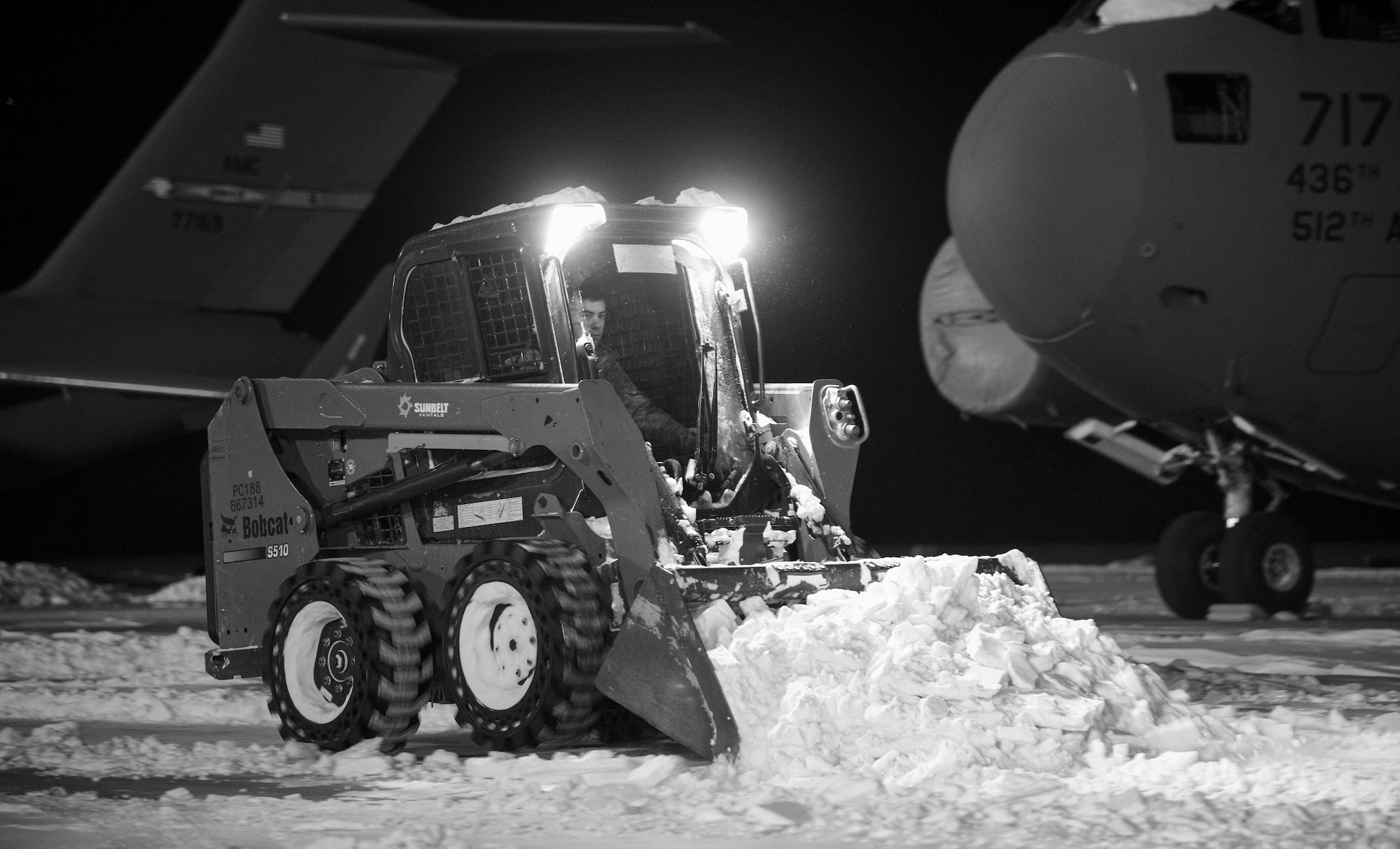 A maintainer from the 736th Aircraft Maintenance Squadron uses a Bobcat to clear snow around a C-17A Globemaster III, Jan. 5, 2018, at Dover Air Force Base, Del. The 436th Operations Support Squadron weather flight recorded eight inches of snow fell on the base from Winter Storm Grayson. (U.S. Air Force photo by Roland Balik)