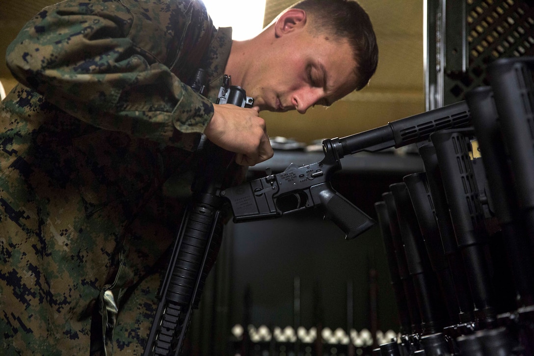 A Marine looks over a dissembled weapon.