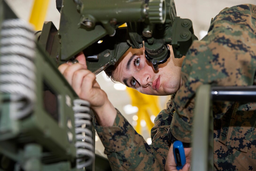 Marine Corps Lance Cpl. Nicholas Wolfe makes repairs to the sight on an M777 towed 155 mm howitzer.