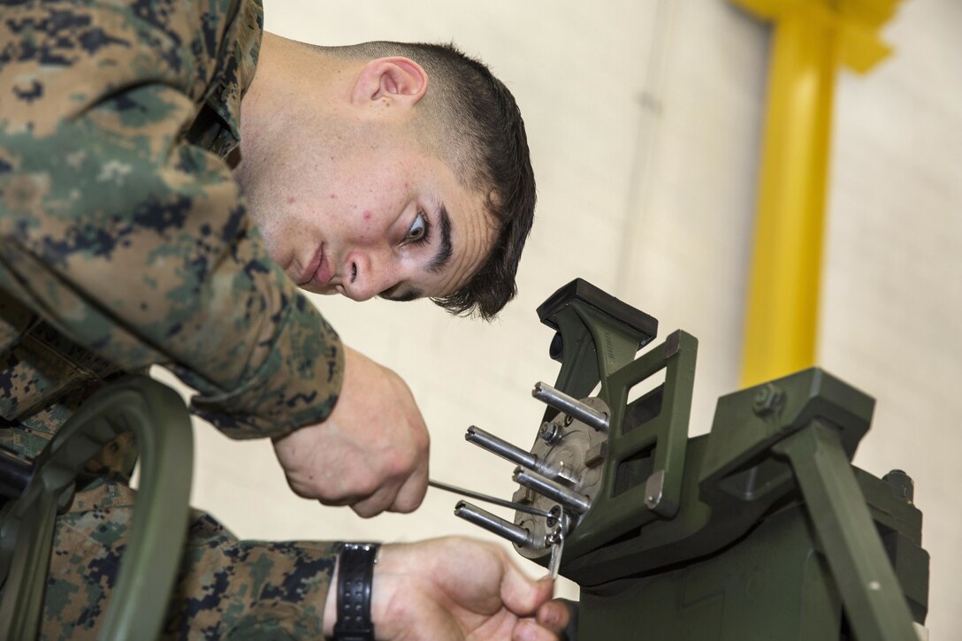 Marine Corps Lance Cpl. Nicholas Wolfe makes adjustments to the sight on an M777 towed 155mm howitzer.