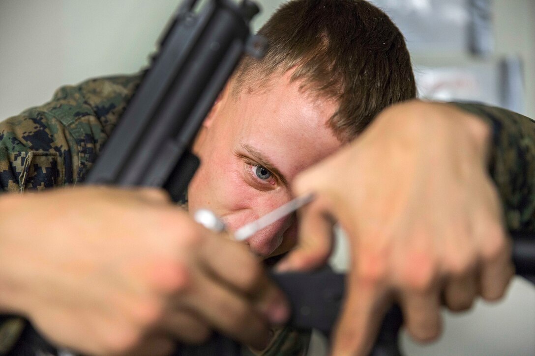 Marine Corps Lance Cpl. Jacob Cooper attempts to remove the hammer on an M16A4 rifle to repair it during an inspection.