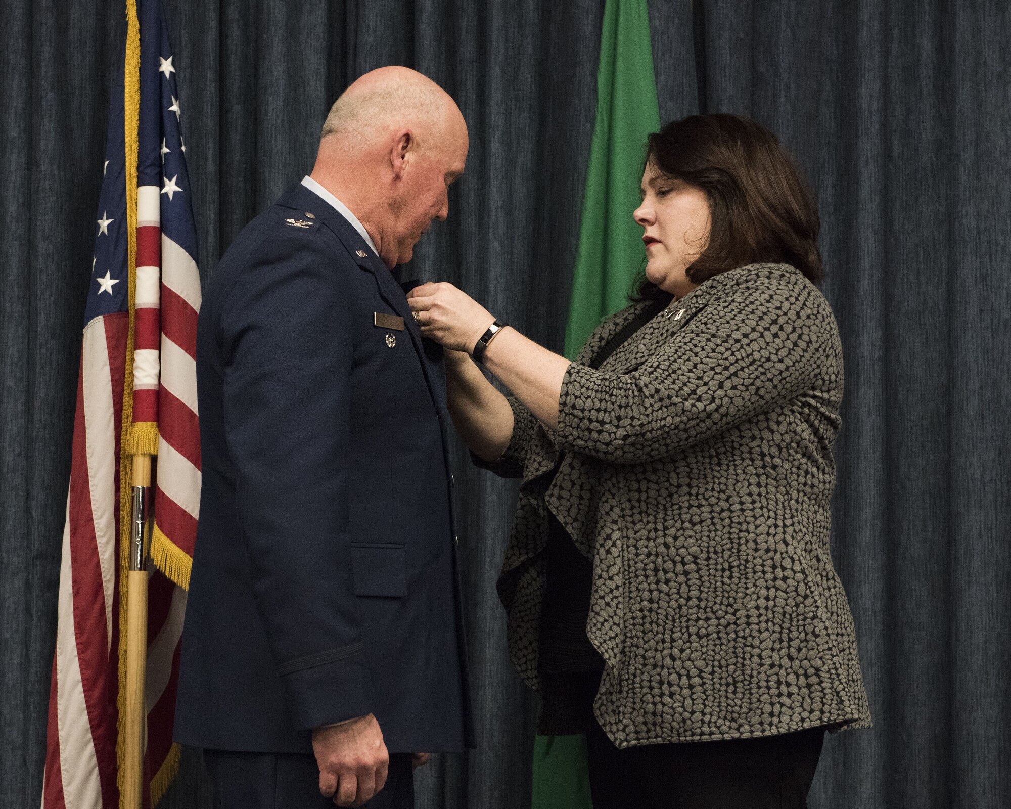 Col. David Dixon, former 141st Maintenance Group commander, watches as his wife, Cathy, places his retirement pin on his lapel during his retirement ceremony January 7, 2018 at Fairchild Air Force Base, Wash. Col. Dixon served more than 30 years in the Air Force, with nearly 19 of those years in the Washington Air National Guard. (U.S. Air National Guard photo by Staff Sgt. Rose M. Lust/Released)