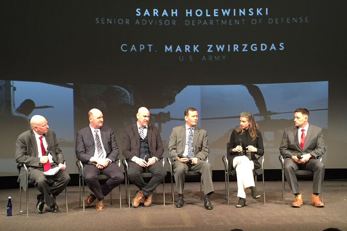 Panelists sit on a stage.