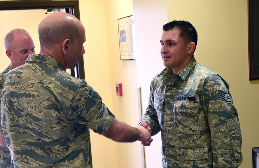 Gen. Mike Holmes, Air Combat Command commander, coins Staff Sgt. Christopher, network operations center technician, during his visit to Creech Air Force Base, Nev., Jan. 6, 2018. Christopher was coined for his work in planning contingency operations. (U.S. Air Force photo/Senior Airman Christian Clausen)
