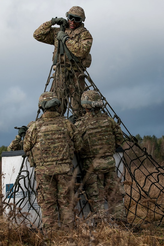 Army Spc. Antonio Ross, top, center, prepares equipment to be slingloaded from a helicopter in Skwierzyna, Poland.