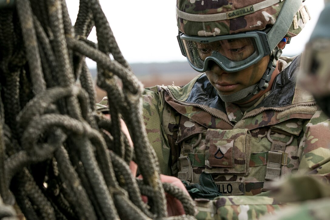 Army Pvt. Adrianne Castillo inspects a rope harness while preparing equipment to be slingloaded from a helicopter in Skwierzyna, Poland.