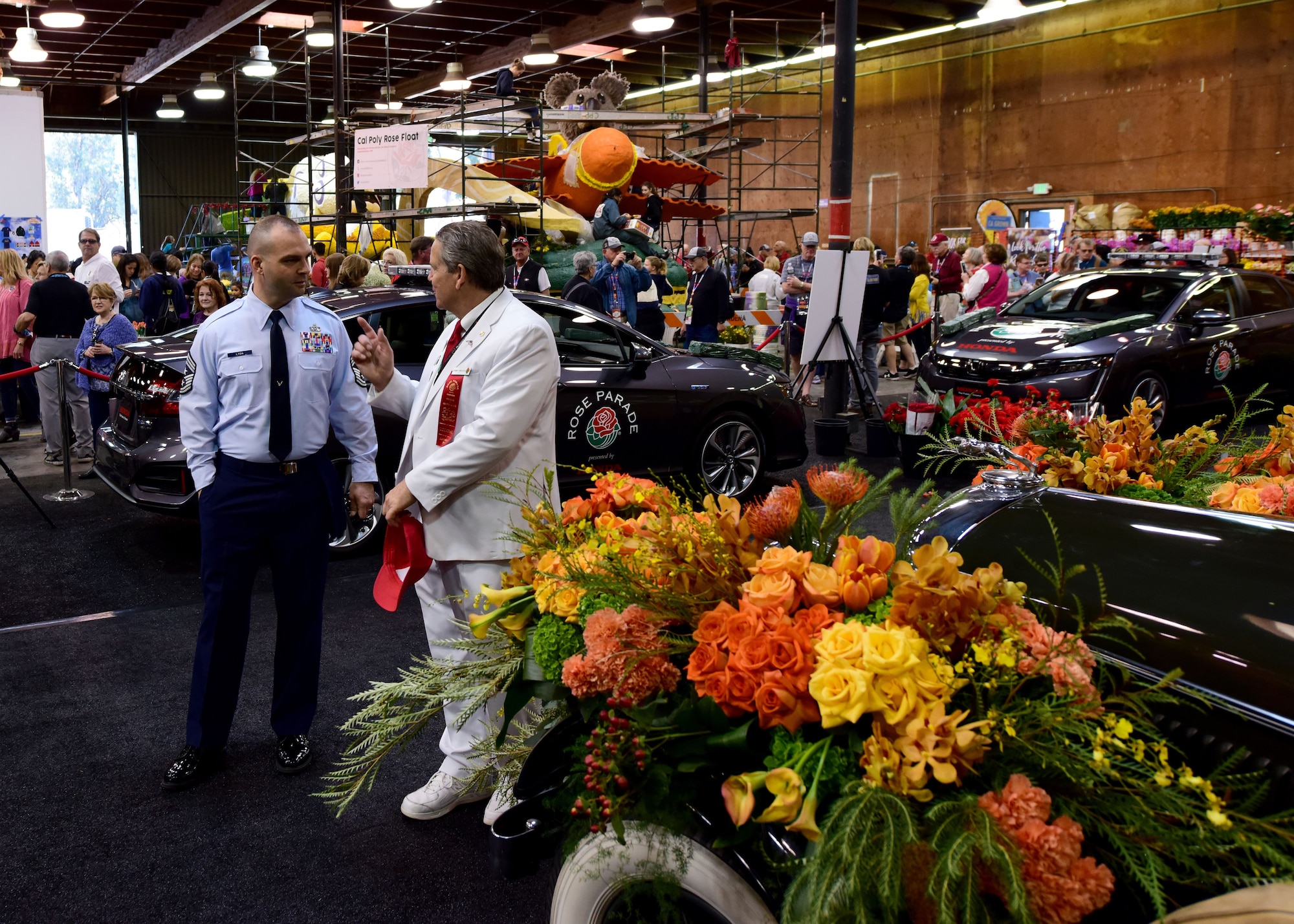 U.S. Air Force Chief Master Sgt. James Lyda, the 509th Bomb Wing command chief, talks to one of the Tournament of Roses representatives during a tour at one of the Decorating Places in Pasadena, Calif., Dec. 30, 2017. The representatives are commonly known as “White Suiters” for their distinctive white uniform, and they are responsible for making sure every aspect of the Rose Parade and Game runs smoothly. (U.S. Air Force photo by Staff Sgt. Danielle Quilla)