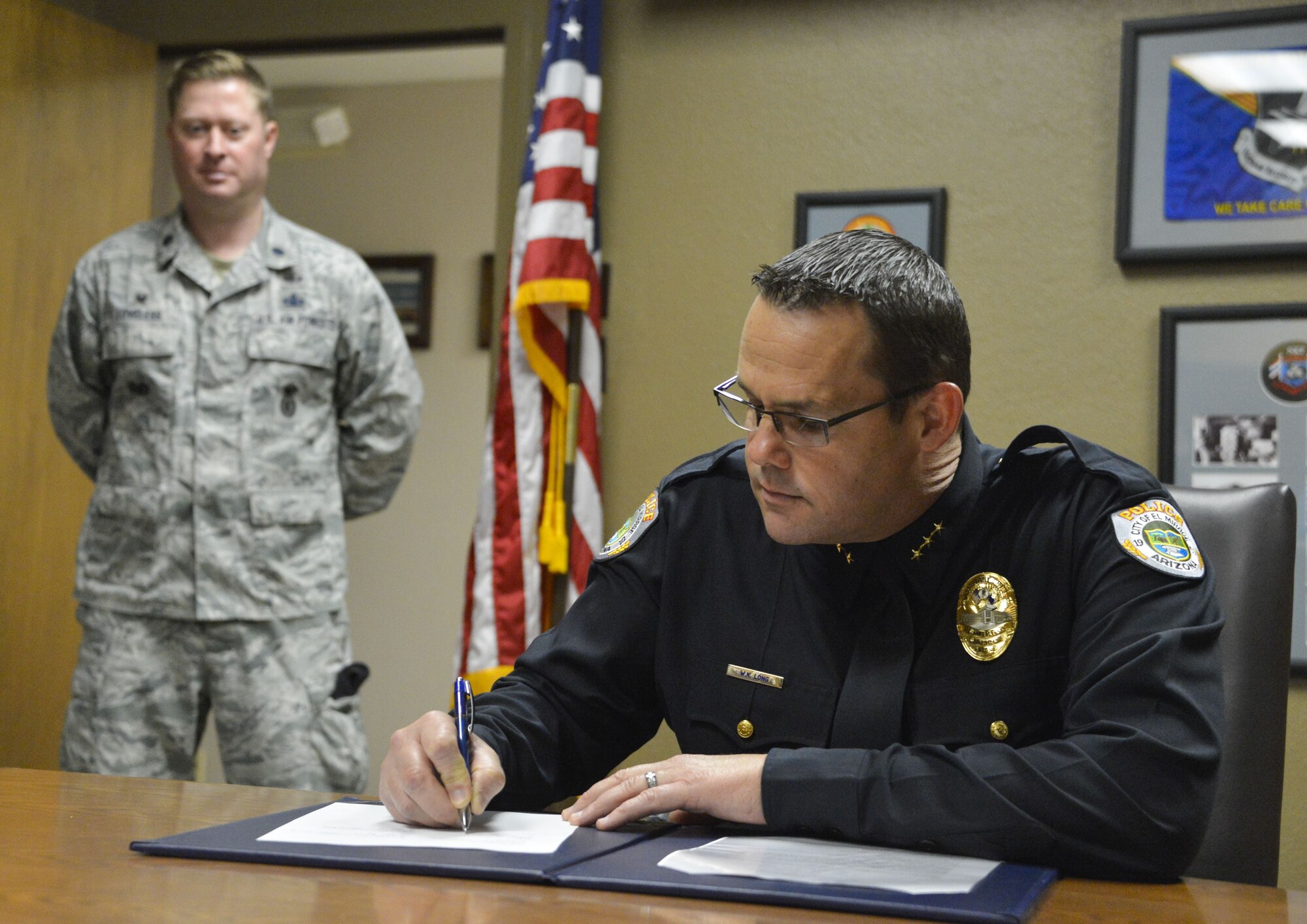 Bill Long, El Mirage Police Department interim police chief, signs the Emergency Vehicle Operators Course Memorandum of Understanding at Luke Air Force Base, Ariz., Jan. 10, 2018. The MSG and 56th Security Forces Squadron will provide the required space for participants to maneuver their vehicles through various obstacles as part of high speed pursuit, avoidance and other forms of EVOC training. (U.S. Air Force photo/Airman 1st Class Caleb Worpel)