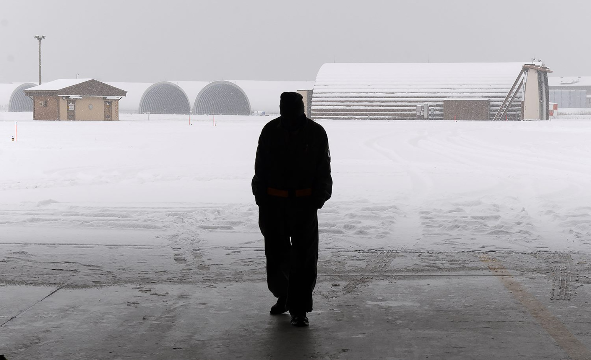 A U.S. Air Force Airman from the 80th Fighter Squadron looks on as snow falls onto the flightline, Jan. 10, 2018 at Kunsan Air Base, Republic of Korea. Even with the snow blowing in from every direction, the mission never stops for the Wolf Pack. (U.S. Air Force photo by Senior Airman Colby L. Hardin)