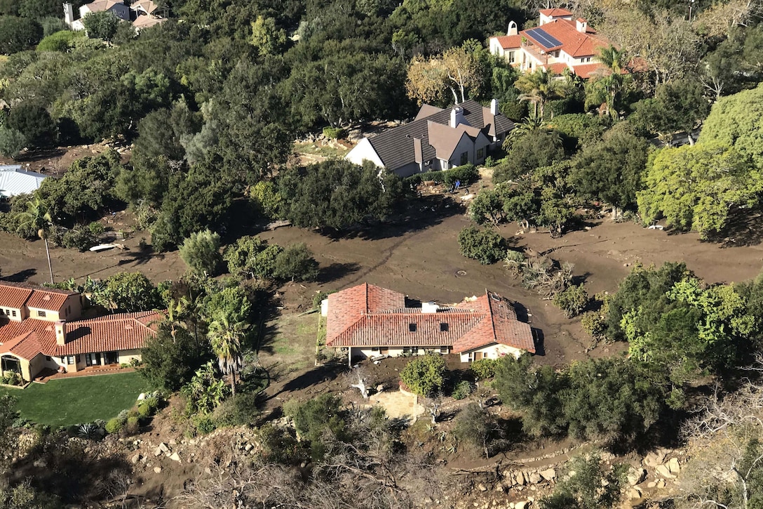 Mud engulfs a home and its surroundings in a residential area, seen from overhead.